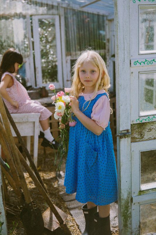 Periwinkle blue kids dress in organic cotton muslin with black polka dots and front pockets by Little Harper Lee