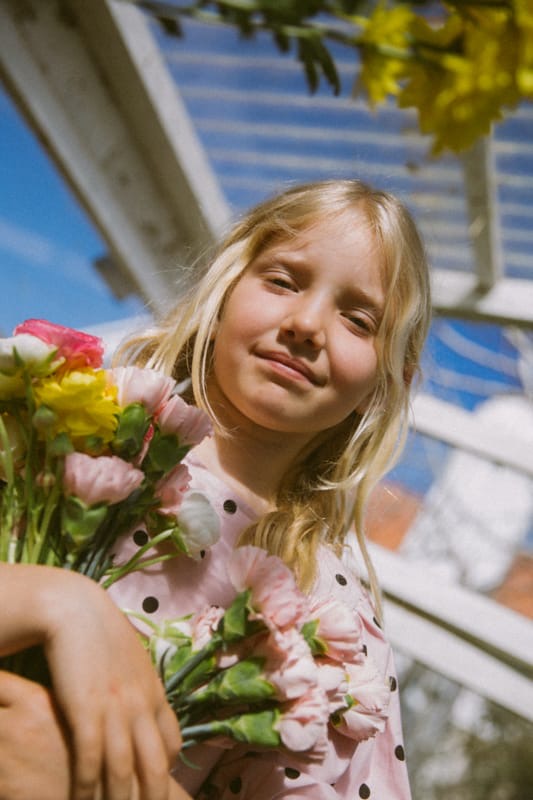Young girl pink dress holding a bouquet of flowers with a blurred background